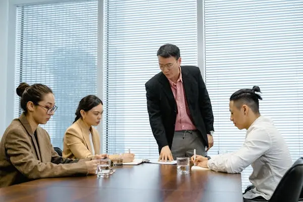 4. Gerente dirigiendo una reunión de revisión de seguros comerciales con empleados en una sala de conferencias
